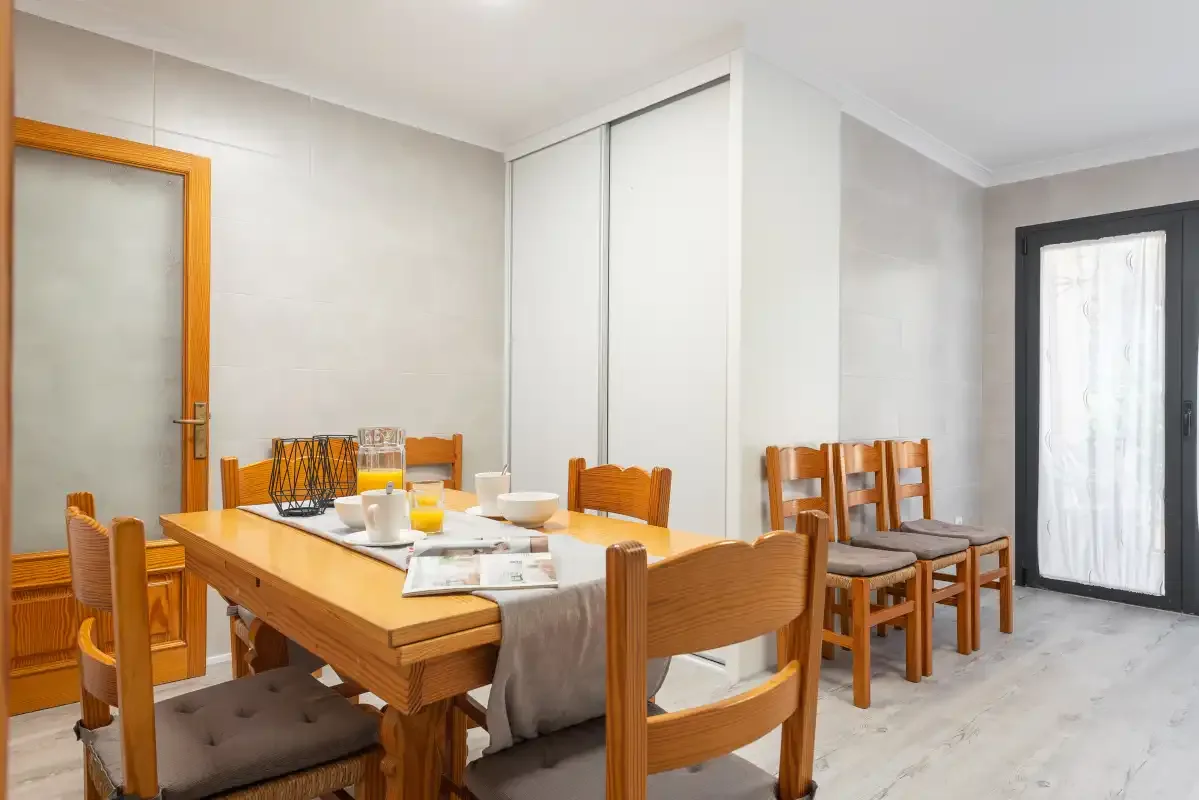 A dining area with a wooden table set with plates and seating.
