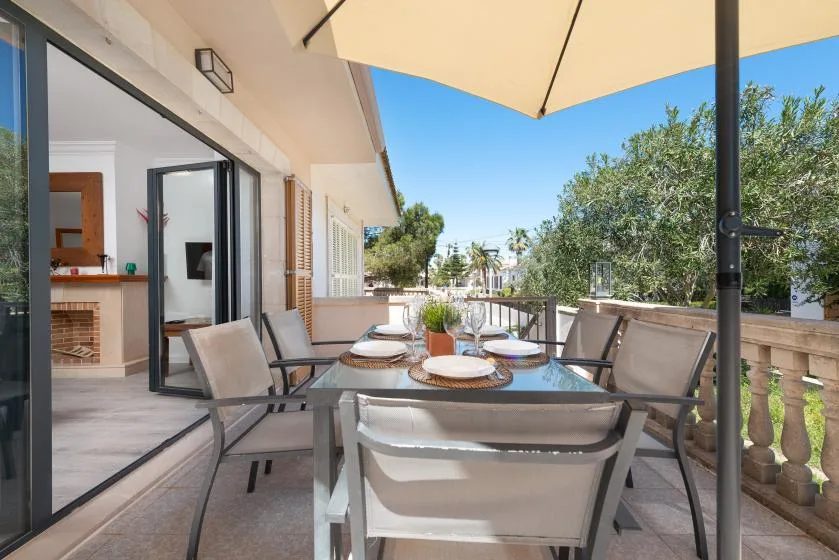 A patio dining area with a table and chairs beneath a large umbrella.