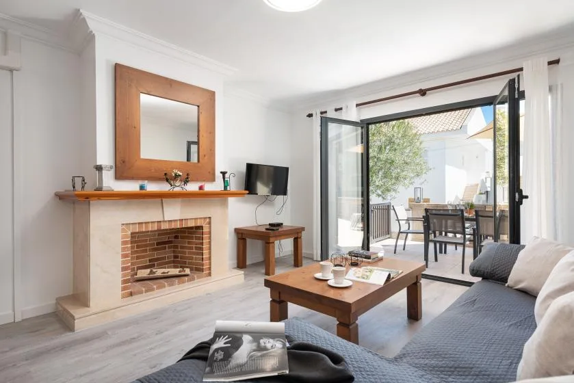 A bright living room with a fireplace and open glass doors to a patio.