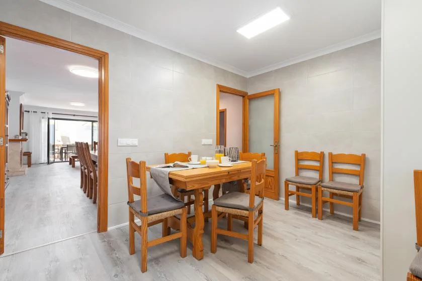 A dining area with a wooden table and chairs, beside an open doorway.
