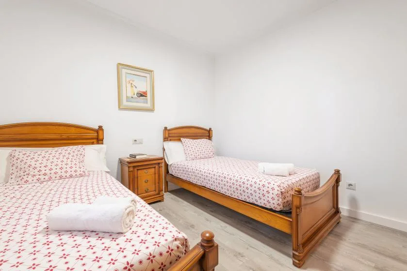 A bright bedroom with two wooden beds dressed in patterned bedding.