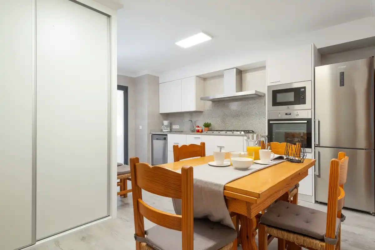 A bright kitchen and dining area with a wooden table and white cabinetry.