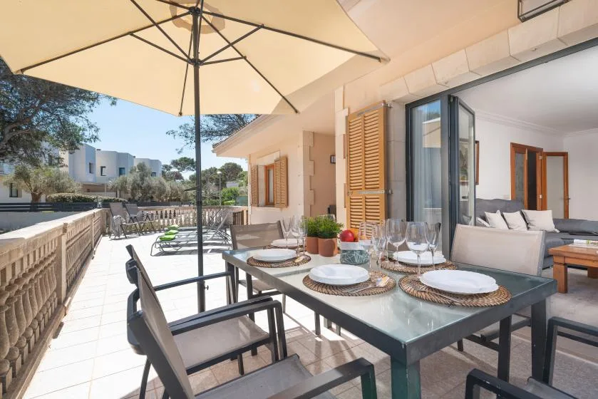 An outdoor dining area beside a patio seating area, shaded by a large umbrella.