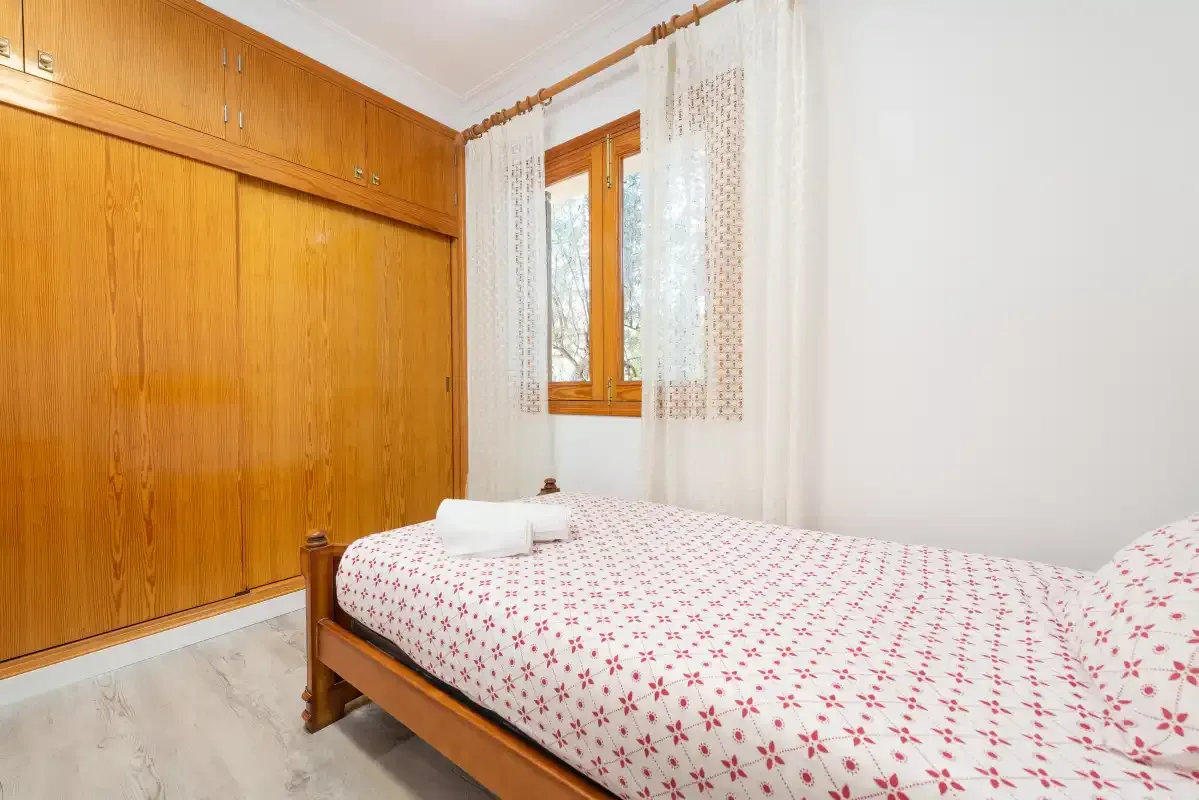 A bedroom with a bed beside a large wooden wardrobe.