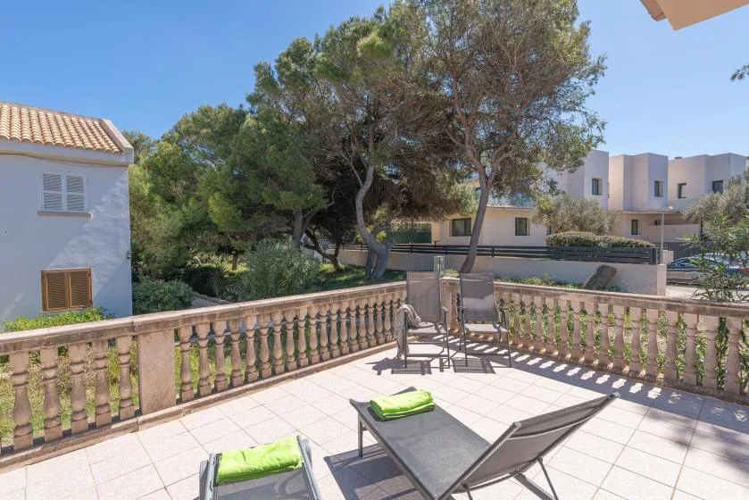 A tiled outdoor terrace with seating overlooks trees and nearby buildings.
