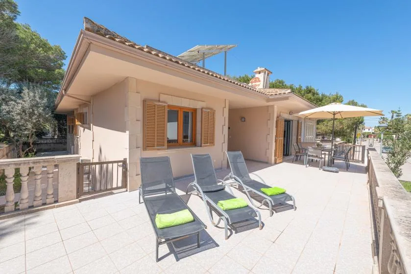 A sunny rooftop terrace has reclining seating and a shaded dining area.