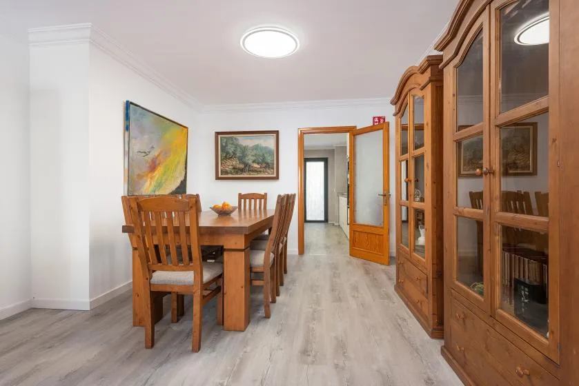 A dining area with a wooden table and glass-front cabinets along the wall.