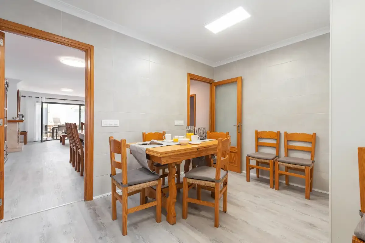 A dining area with a wooden table and chairs beside an open doorway.