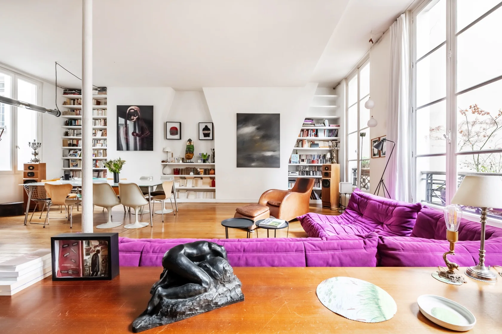 Una sala luminosa con asientos morados y ventanas altas.