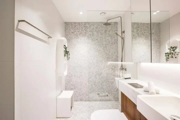 Un baño luminoso con ducha y un lavabo largo.