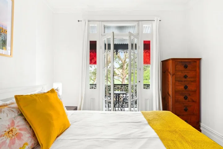 Un dormitorio con una cama frente a puertas abiertas y vistas a la vegetación.