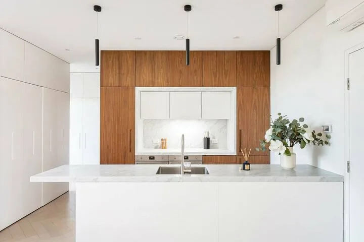 Una cocina moderna con una isla blanca y gabinetes de madera.