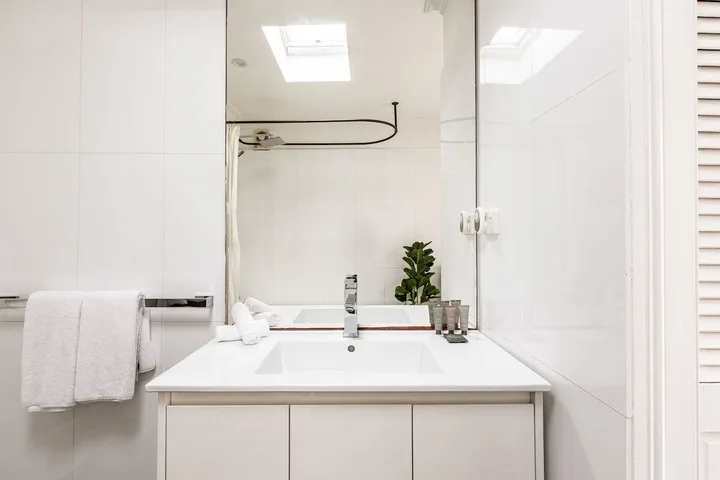Un lavabo de baño luminoso con un espejo amplio y toallas dobladas.