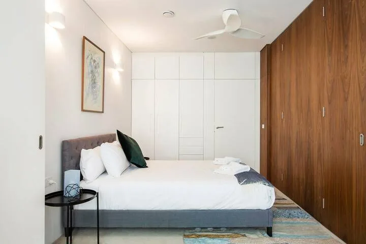 Un dormitorio con una cama bien hecha, arte en la pared y armarios de madera.
