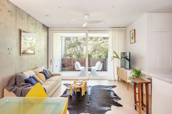 Una sala luminosa con asientos y puertas de vidrio que dan a un balcón.