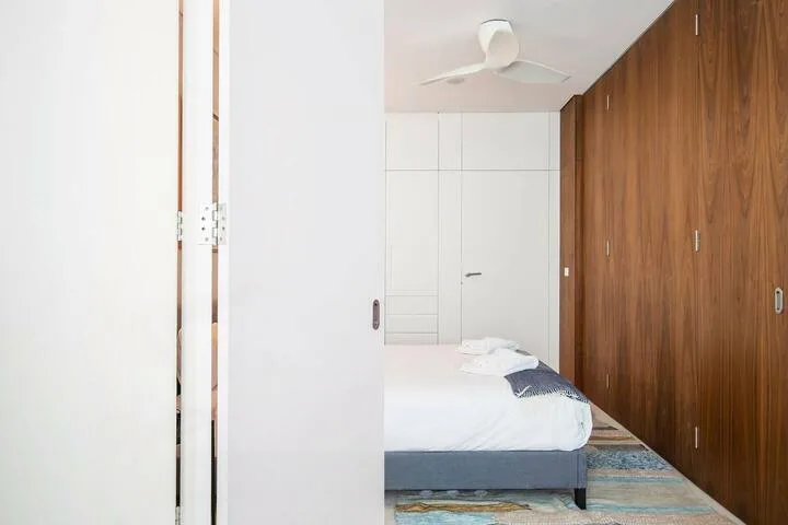Un dormitorio con una cama junto a un armario de madera de suelo a techo.