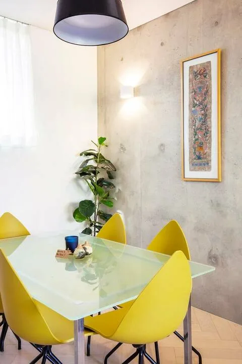 Un comedor con una mesa de vidrio y asientos amarillos.