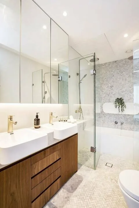 Un baño luminoso con tocador doble y ducha de vidrio.