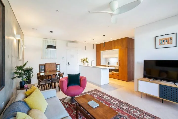 Una luminosa sala de estar diáfana con zona de asientos, comedor y cocina.