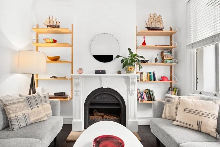 Una sala luminosa con asientos, una chimenea y estantes.
