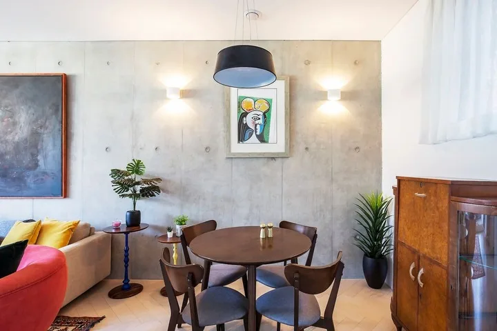 Zona de comedor y estar con una mesa redonda y asientos de colores.