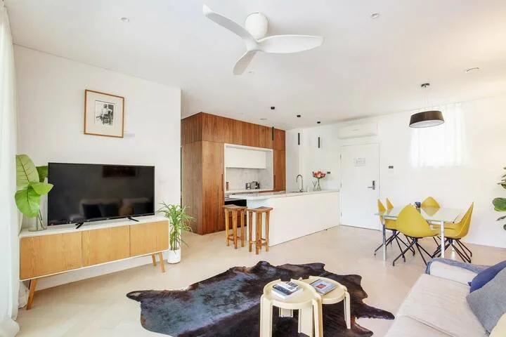 Una luminosa sala-comedor con televisor, mesa y barra de cocina.