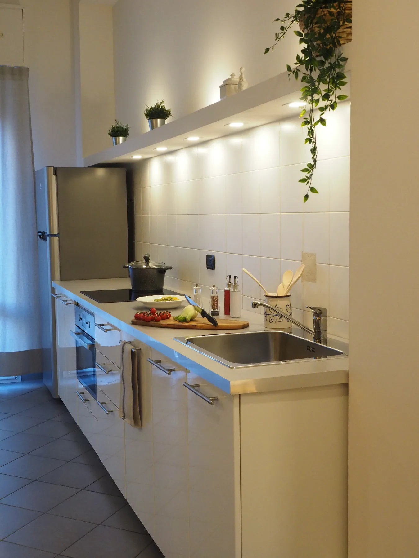 Una cocina luminosa con una encimera larga, fregadero y zona de cocción.