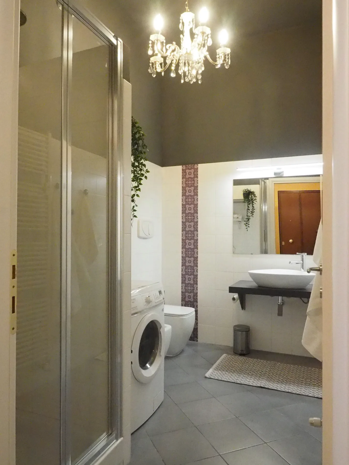 Un baño con ducha de vidrio, lavabo y lavadora.