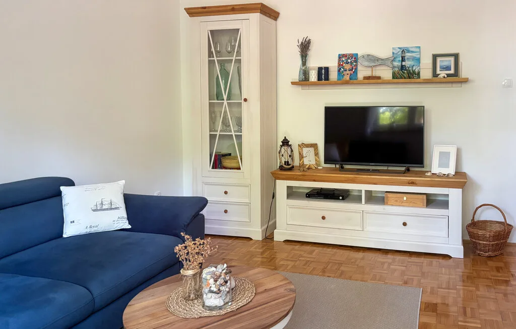 A living room with blue seating, a television, and a wooden coffee table.