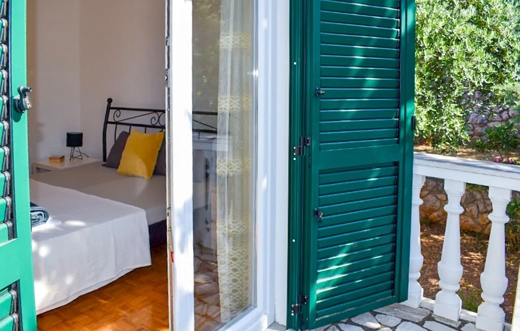 A bedroom with a bed beside an open doorway to a balcony.