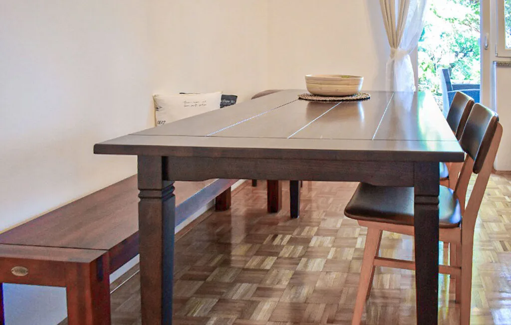 A dining area with a long wooden table, bench, and chairs beside a window.