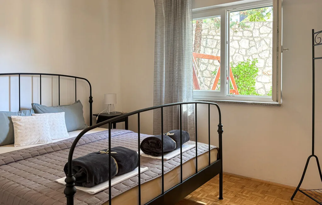 A bedroom with a metal bed beside a bright window.