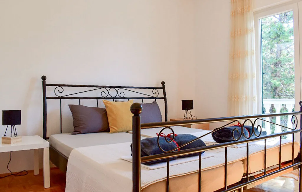 A bedroom with a metal bed, pillows, and a large window.