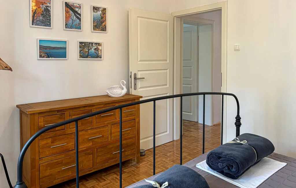 A bedroom with a wooden dresser, framed pictures, and a doorway.