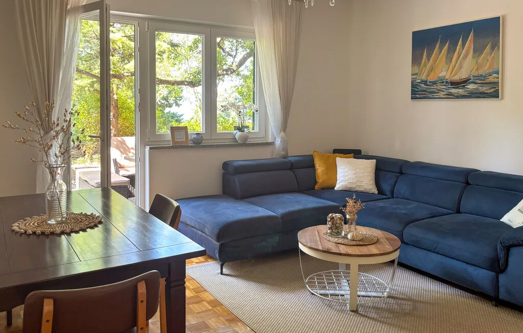 A bright living room with blue seating, a coffee table, and large windows.
