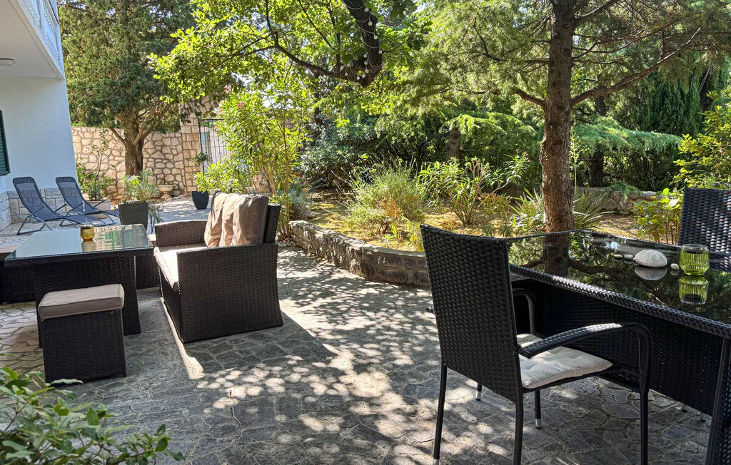 A shaded outdoor patio with seating and leafy garden plants.