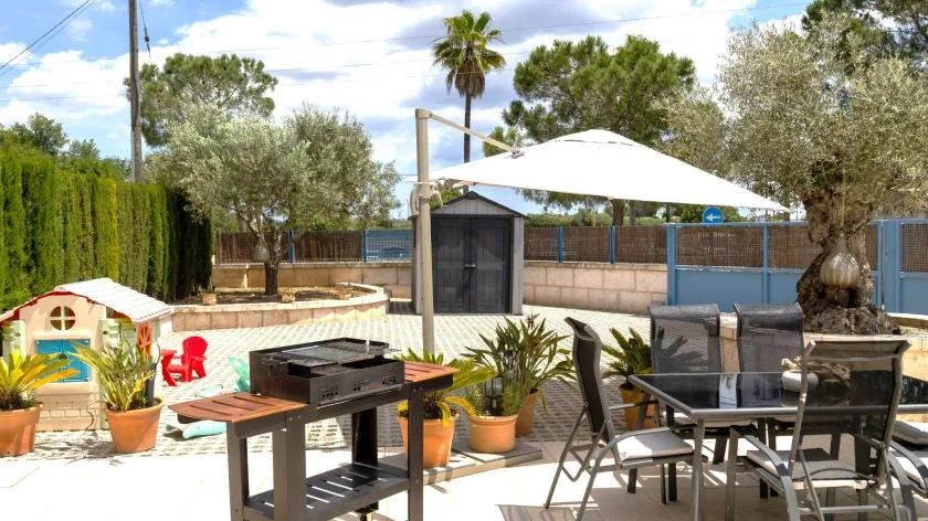 Un patio al aire libre con una mesa de comedor y una sombrilla grande junto a una piscina.