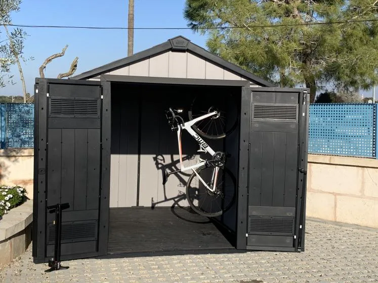 Una bicicleta está estacionada dentro de un cobertizo oscuro abierto.