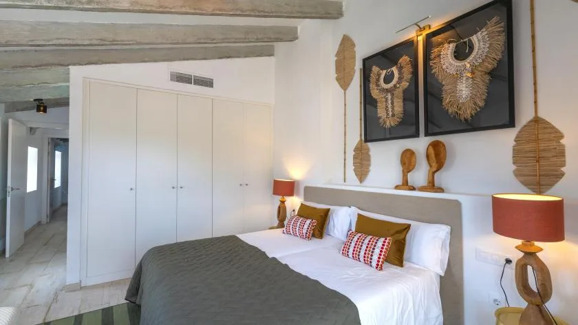 Un dormitorio con una cama bien tendida y cuadros sobre el cabecero.