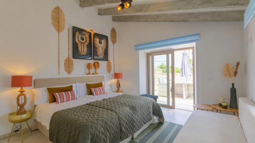 Un dormitorio con la cama tendida y puertas de vidrio que dan a un balcón.
