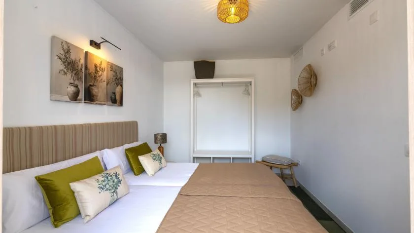 Un dormitorio con una cama tendida y cuadros en la pared.