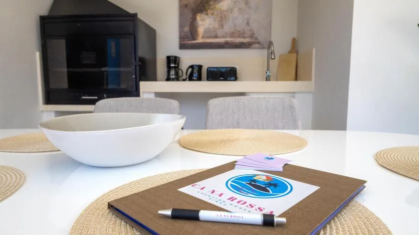 Una mesa de comedor con individuales tejidos y un cuenco blanco está frente a una encimera de cocina.