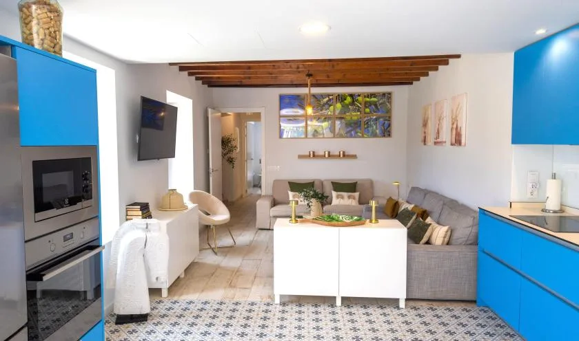 Una sala luminosa se conecta con una cocina de gabinetes azules y una isla central.