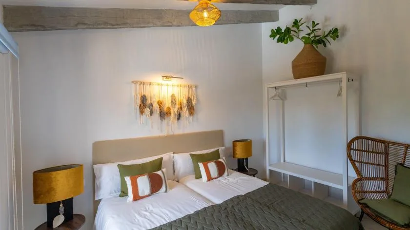 Un dormitorio con una cama bien tendida y decoración tejida en la pared.