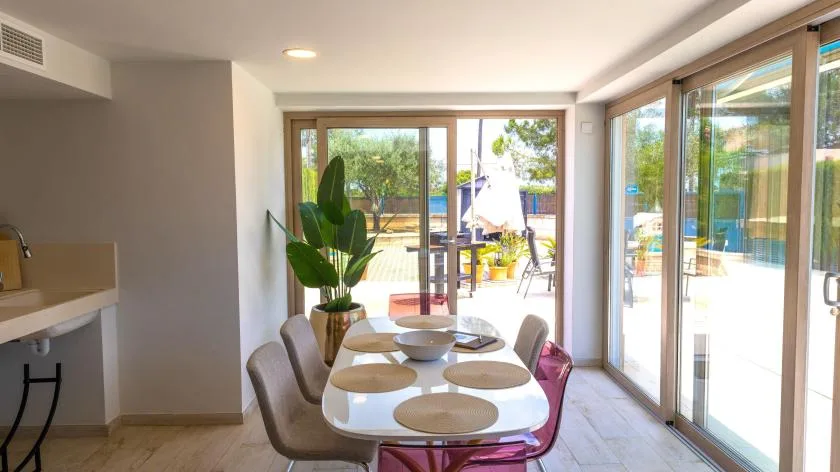 Comedor con una mesa junto a grandes puertas de vidrio que dan a un patio.