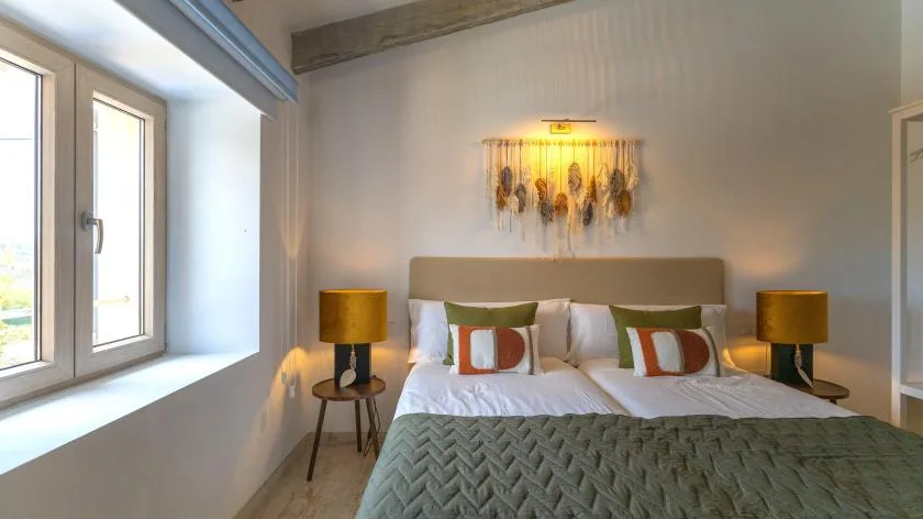 Un dormitorio con una cama, mesitas de noche y una ventana grande.