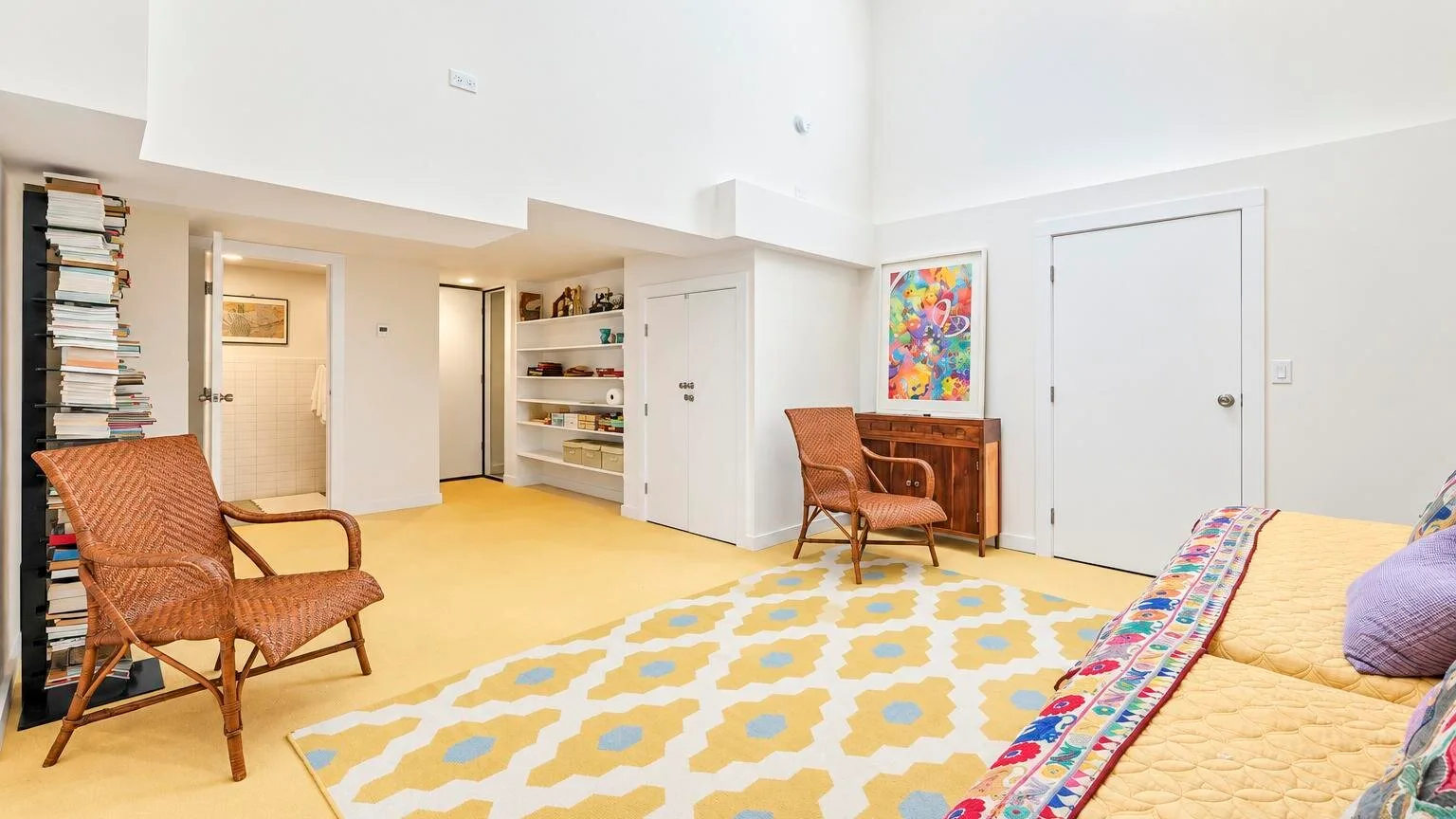 Una sala luminosa con asientos de mimbre, una alfombra estampada y un tapiz colorido.