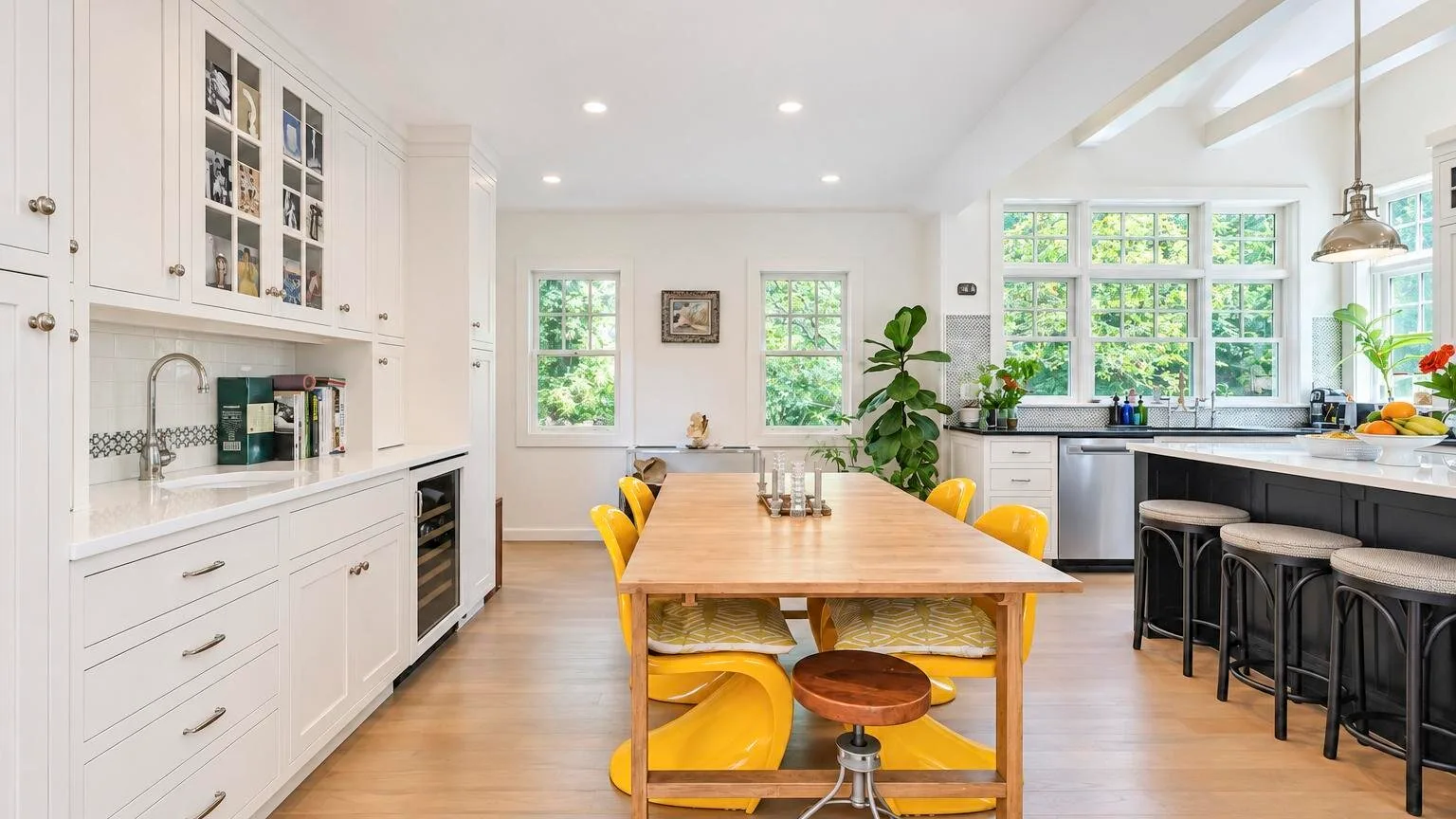 Una cocina luminosa con comedor, mesa de madera y asientos amarillos.