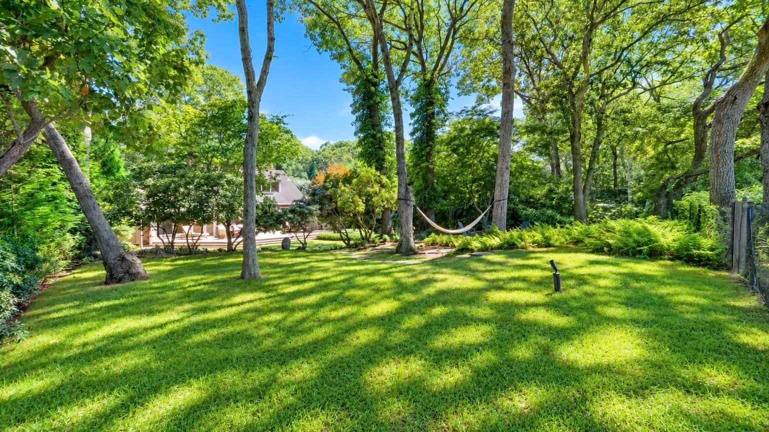 Un jardín frondoso con una hamaca colgada entre los árboles.