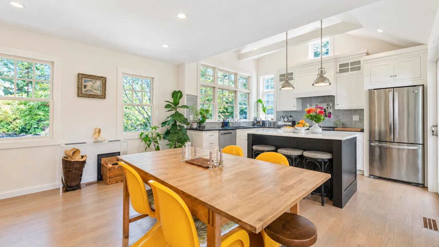 Una luminosa cocina-comedor de concepto abierto con una mesa de madera y asientos amarillos.
